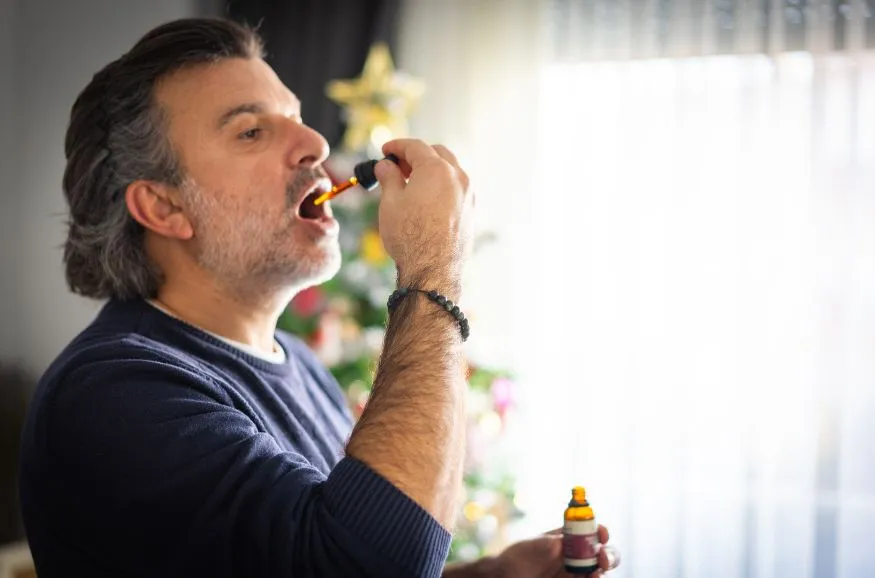 Man taking liquid medicine with dropper.