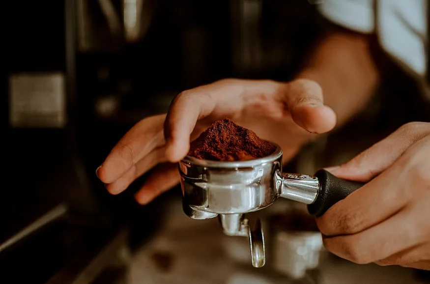 Barista preparing espresso with coffee grounds.