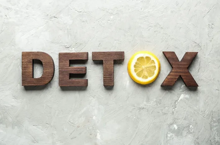 Detox sign with lemon on concrete background.
