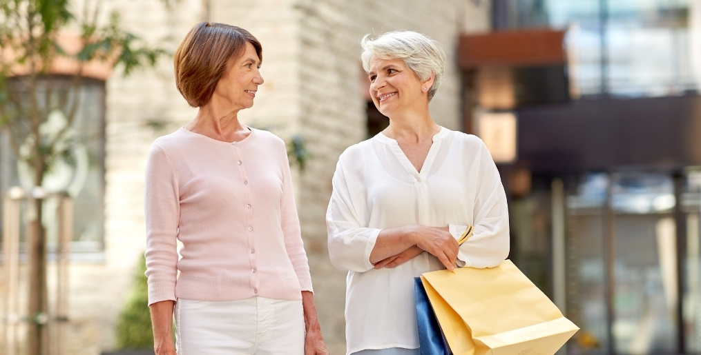 Two women walking and carrying shopping bags.