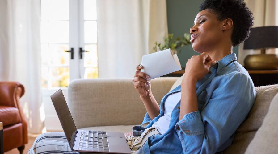Woman enjoying cool air with laptop at home.