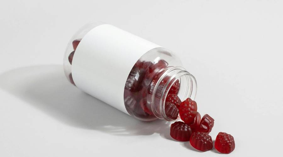 Open bottle spilling red gummy vitamins