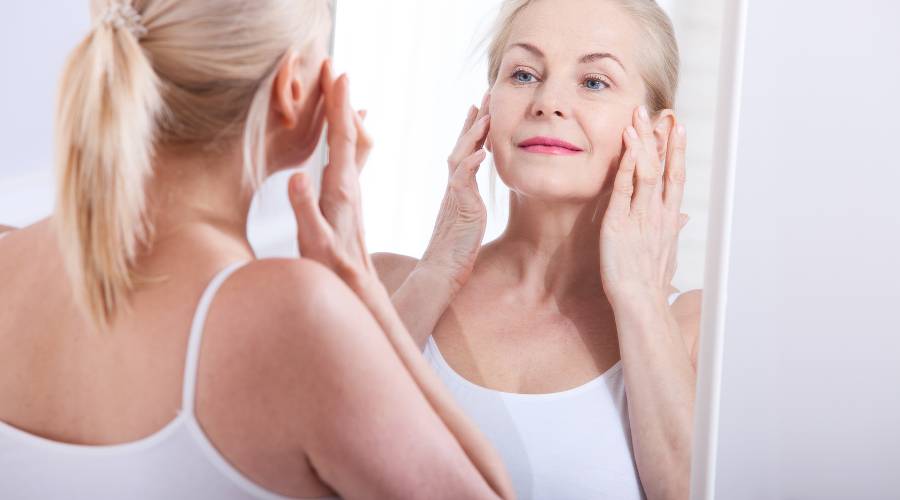 Woman examining her face in the mirror